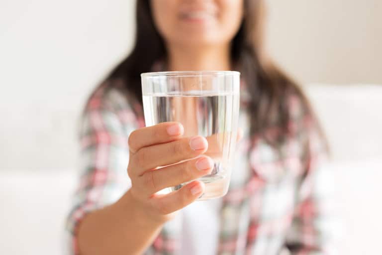 woman holding out glass of water